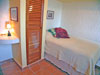 A small guest bedroom has full-size bed and half bath. Garden view.