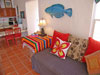 Small living room has sofa and twin daybed. Glass door to large balcony. Staircase to downstairs unit.