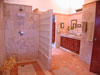 Large bathroom with double vanity, shower and dressing room with garden view. Louvered shutters allow for a view of the bay from the shower.